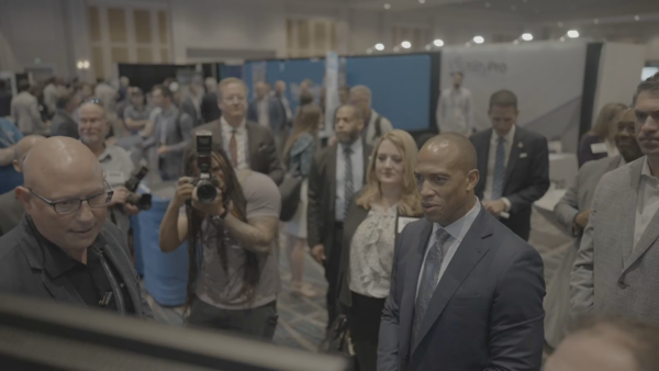 A crowd gathers around HUD Secretary Scott Turner as he visits the Aareas Interactive booth at the 2025 MHI Congress & Expo, viewing the Home Configurator demonstration.