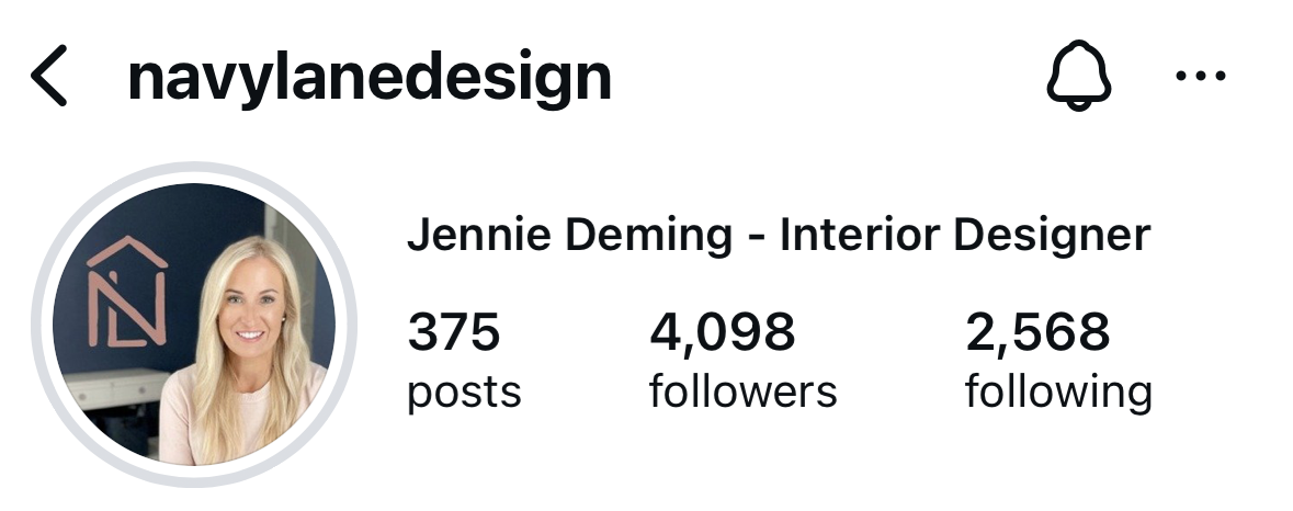 Instagram profile photo of Jennie Deming from Navy Lane Design — smiling in front of a dark background with a stylized “NL” logo.